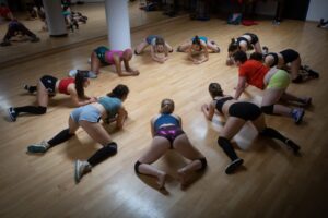 Plusieurs femmes au sol à quatre pattes forment un cercle en dansant le twerk